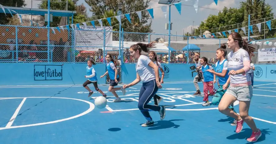 niños jugando fútbol cancha comunitaria segura